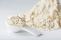 A mountain of soy protein isolate in powder with a measuring spoon on a white background. Royalty Free Stock Photo