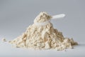 A mountain of soy protein isolate in powder with a measuring spoon on a white background.