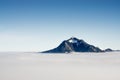 Mountain stick out of inversion fog cloud layer. Above the clouds concept for outstanding Business ideas, foresight and