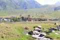 Mountain stream against the backdrop of village houses. Summer mountain landscape. Kyrgyzstan Royalty Free Stock Photo