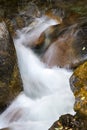 Mountain stream cascades in closeup between colorful boulders and moss