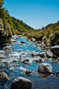 Mountain stream flowing over rocks under blue sky Royalty Free Stock Photo