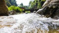 A mountain stream flows rapidly between the rocks on a narrow bridge in the rainforest of the Cameron Highlands, Malaysia. The Royalty Free Stock Photo