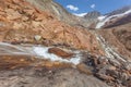 Mountain stream over rocks smoothed by the glacier seen in the background