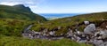 A mountain stream between rocks and green hills. Summer panorama with an aerial perspective on the ocean on the horizon. Lofoten Royalty Free Stock Photo