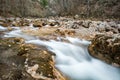 Mountain stream swift among rocks, coniferous pine forest, blurry water movement, close-up Royalty Free Stock Photo