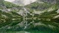 Mountain stream with view of rocky mountains and lake with transparent water Royalty Free Stock Photo
