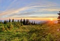 Mountain Sunset: A Golden Orange Glow Silhouettes the Distant Peaks and Wooded Landscape