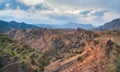 Mountain terraces. A rocky ledge stretching into the distance against the background of red textured mountains covered with sparse Royalty Free Stock Photo