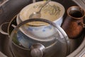 A mountain of unwashed utensils in a kitchen sink. Desolation and mess