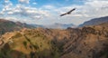 Mountain valley with a soaring eagle. A rocky ledge stretching into the distance against the background of mountains covered with Royalty Free Stock Photo