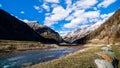 Mountain valley with stream, trees, small hut and dried Livigno lake, Alps, Italy Royalty Free Stock Photo