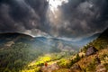 Mountain Valley with sunbeams in cloudy sky