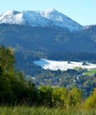 South German landscape with a village in the valley, mountain forest and majestic mountain with snow in the background Royalty Free Stock Photo