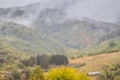 Mountain from view with small village and flow fog. Foggy summer morning in the mountains and a small village. Country road in the Royalty Free Stock Photo