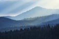 Mountain view on a sunny day. Sunrays from clouds shining down to mountains.  Silhouettes of trees on the mountains Royalty Free Stock Photo