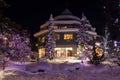 Mountain village after snowfall in night. Christmas illumination - trees, garlands and night lights, snow-covered houses, pine tre Royalty Free Stock Photo