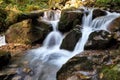 Mountain waterfall flows among green forest and runs down the beautiful gray stones. Amazing summertime wallpaper background Royalty Free Stock Photo