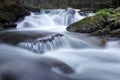 Mountain waterfall flows among green forest and runs down the beautiful gray stones. Amazing summertime wallpaper background Royalty Free Stock Photo