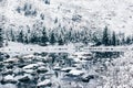 Mountain winter lake with the reflection of rocks in the water surface.