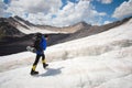 A mountaineer with a backpack walks in crampons walking along a dusty glacier with sidewalks in the hands between cracks Royalty Free Stock Photo