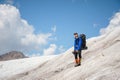 A mountaineer with a backpack walks in wheelchairs, stands on a dusty glacier with sneakers in the hands between cracks Royalty Free Stock Photo