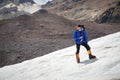 A mountaineer with a backpack walks in wheelchairs, stands on a dusty glacier with sneakers in the hands between cracks Royalty Free Stock Photo