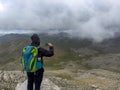 mountaineer capturing the views after the rain from the high point of the summit mountains with his phone Royalty Free Stock Photo