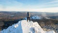 The mountaineer climbed the mountain top, man hiker standing at the peak of rock covered with ice and snow, view from Royalty Free Stock Photo