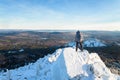 The mountaineer climbed the mountain top, man hiker standing at the peak of rock covered with ice and snow, view from Royalty Free Stock Photo