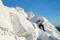 The mountaineer climbing the mountain top covered with ice and snow, man hiker going at the peak of rock. Winter season. Royalty Free Stock Photo