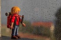 The mountaineer doll of Playmobil watching as it rains through the window and can not go out to the mountain
