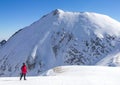 Mountaineer girl standing in a snowed landscape with a hight mountain behind her