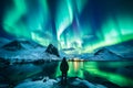 The mountaineer looks admiringly at the northern lights or Aurora phenomenon.