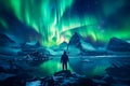 The mountaineer looks admiringly at the northern lights or Aurora phenomenon.