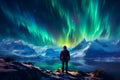 The mountaineer looks admiringly at the northern lights or Aurora phenomenon.