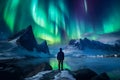 The mountaineer looks admiringly at the northern lights or Aurora phenomenon.