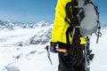 A mountaineer man holds an ice ax high in the mountains covered with snow. Close-up from behind. outdoor extreme outdoor