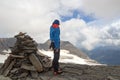 Mountaineer man standing next to cairn on summit of Eiswandbichl and looking at mountain snow and glacier panorama with summit