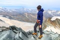 Mountaineer man standing on summit of mountain Allalinhorn and looking to panorama view with mountain Matterhorn in Pennine Alps,