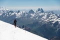 Mountaineer in the mountains strolls along the snow slope against the background of snow-capped peaks