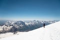 Mountaineer in the mountains strolls along the snow slope against the background of snow-capped peaks