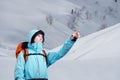 The mountaineer pointing at peak, standing against a winter mountain landscape. Royalty Free Stock Photo