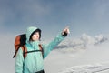 The mountaineer pointing at peak, standing against a winter mountain landscape. Royalty Free Stock Photo