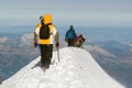 Mountaineer reaches the top of a snowy mountain in a sunny winter day