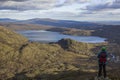 A mountaineer remains standing observing the lake of sanabria with beautiful clouds in the sky and a calm and beautiful scenary. Royalty Free Stock Photo