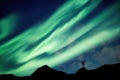 Mountaineer standing on top of mountain with Aurora Borealis glowing in the night sky on arctic circle Royalty Free Stock Photo
