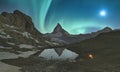 Mountaineer stands in front of the lake where Aurora Borealis showing his best show, Matterhorn area. Switzerland