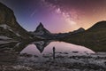 Mountaineer stands in front of the lake where Milky Way galaxy, Matterhorn 4478m and Dente Blanche 4357m reflected in the Riffelse