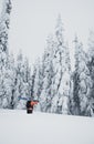 Mountaineer walking up along a snowy mountain with the skis in the backpack. Skier on the climbing track for freeride-descent.